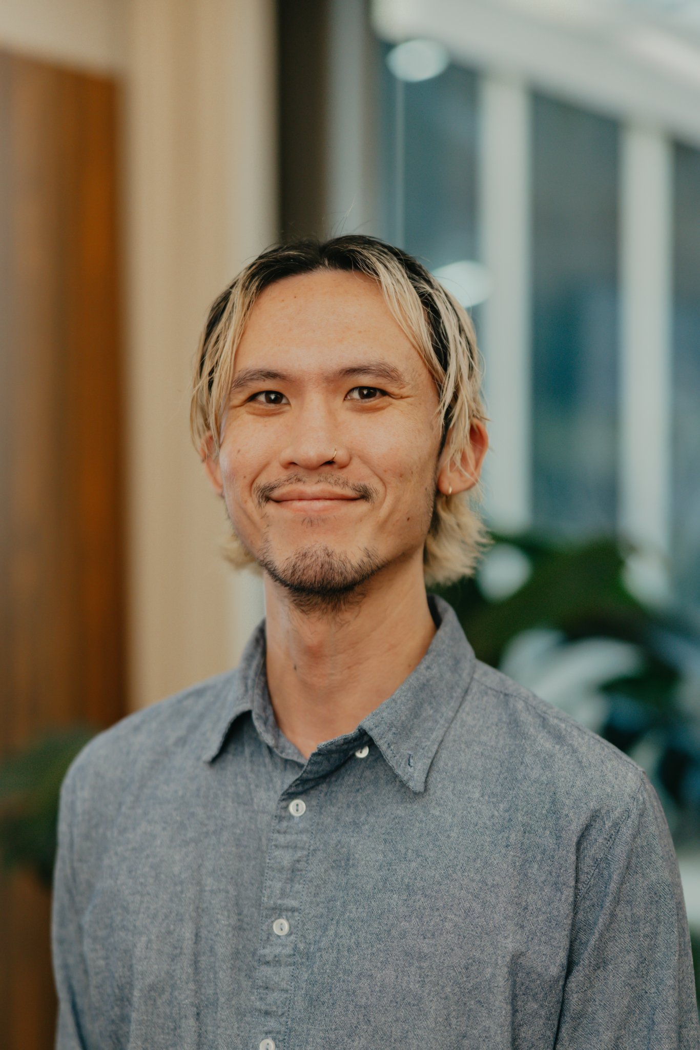 Professional headshot of a man with light-coloured hair wearing a grey shirt.