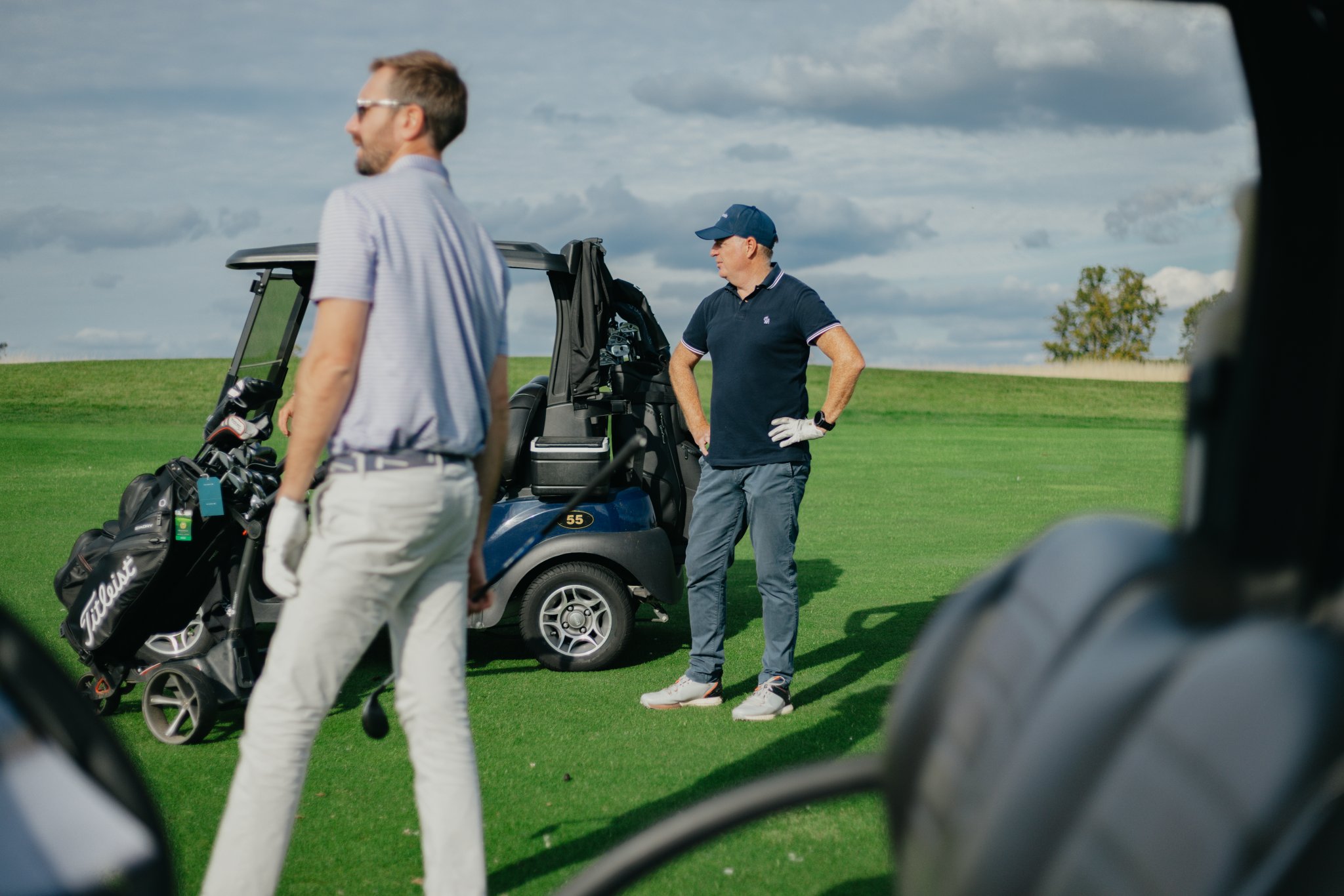Two men standing beside a golf buggy during a golf event.