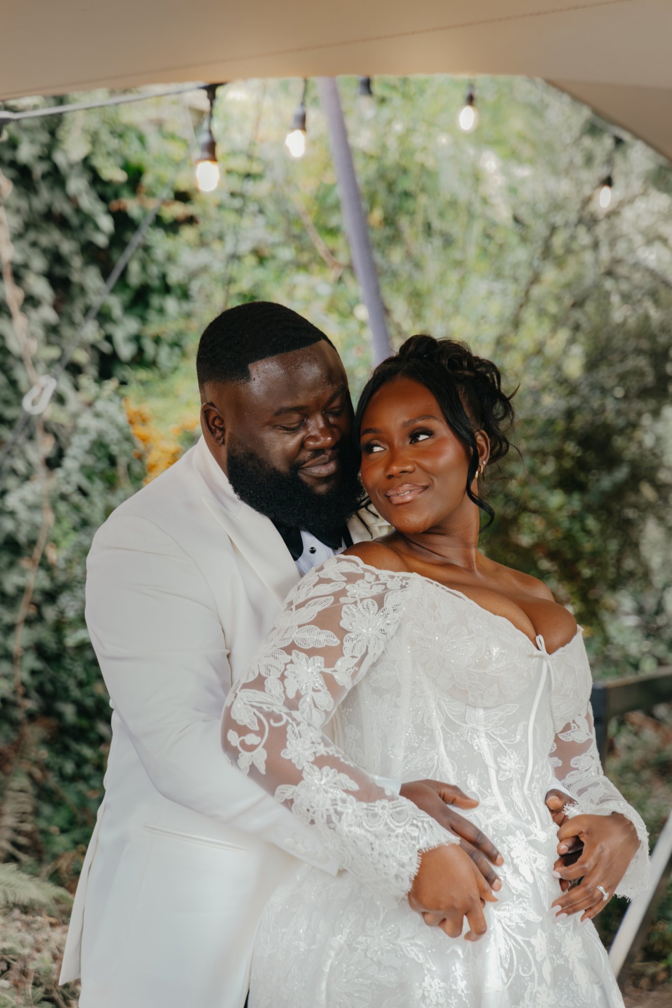 Close-up portrait of a bride and groom embracing and smiling at each other in a garden.