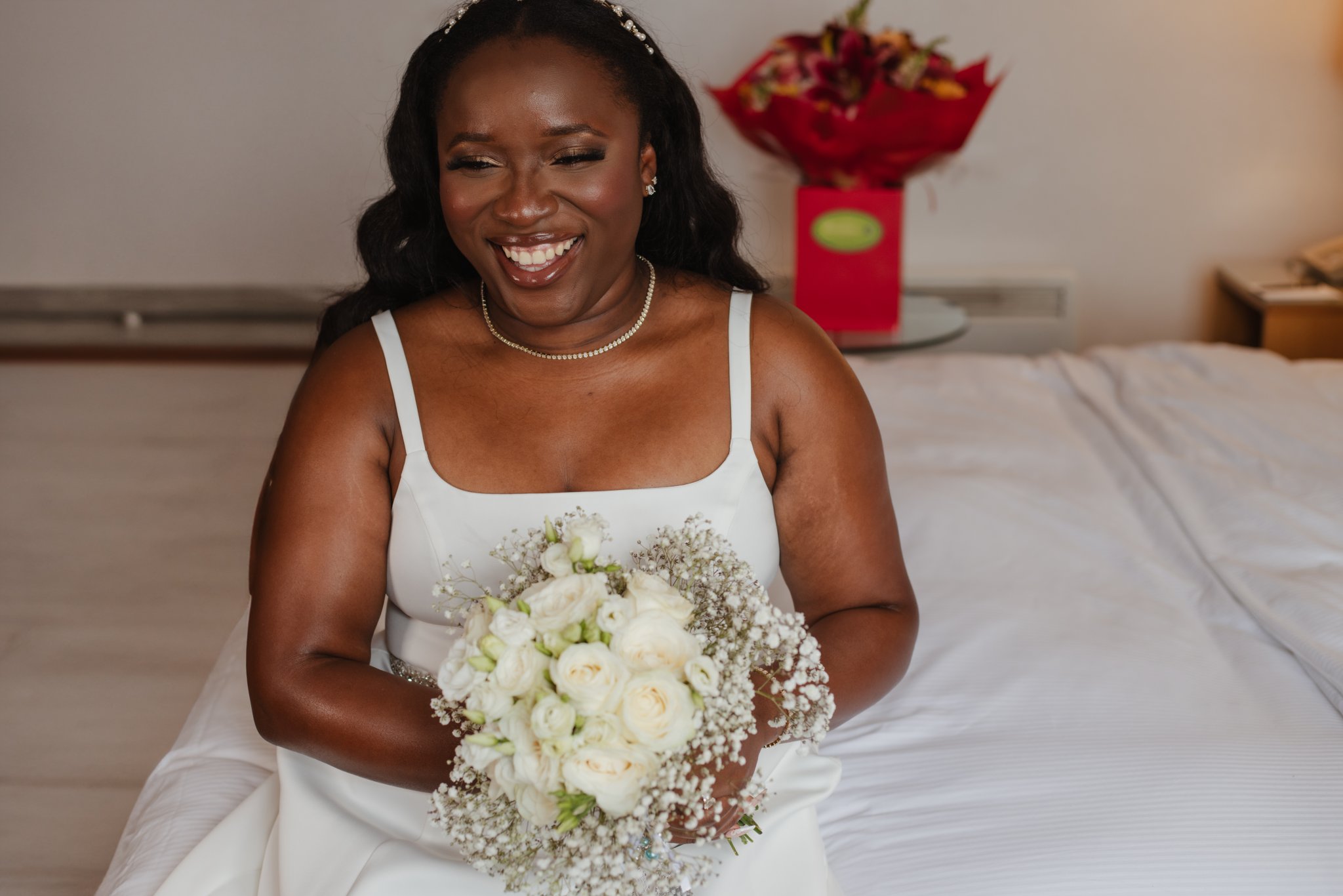 Smiling bride holding a bouquet of white roses and baby's breath before her wedding ceremony.