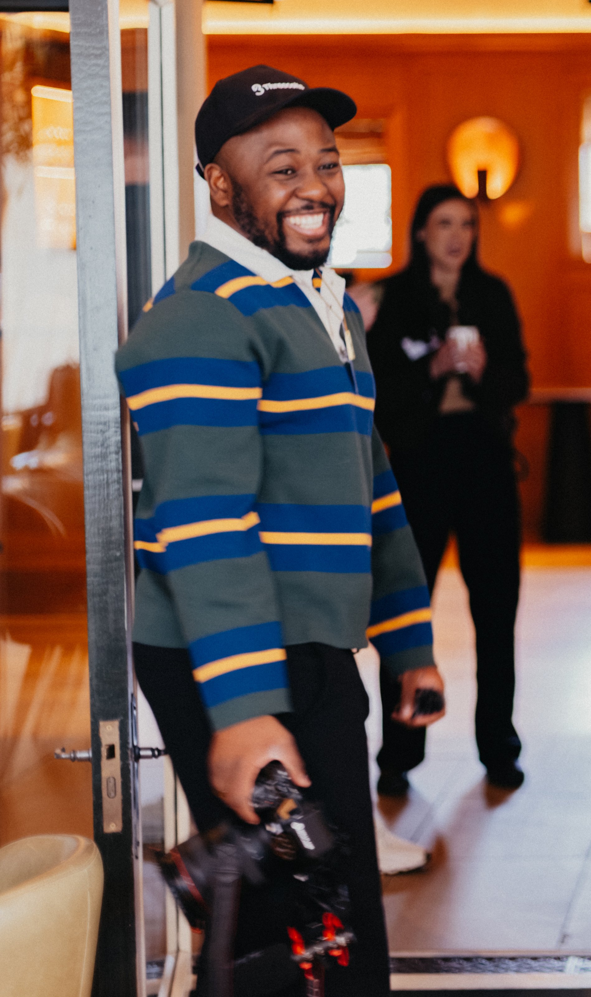 Lionel Odelana smiling while standing in an indoor event space. Lionel Odelana